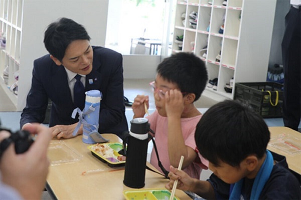 El alcalde que contempla a los niños que comen el almuerzo